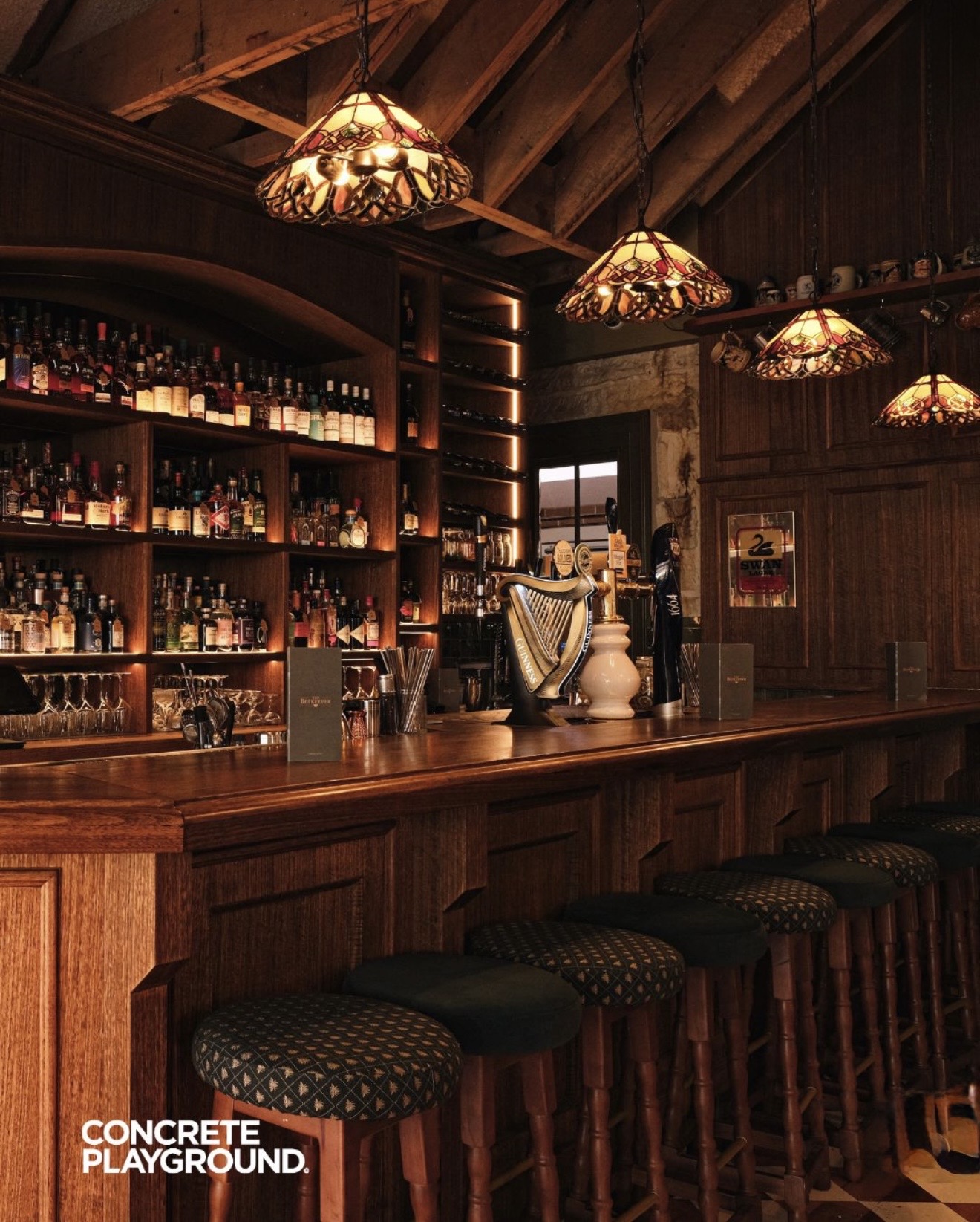 Completed timber-panelled bar with backlit spirits shelving and heritage pendant lighting
