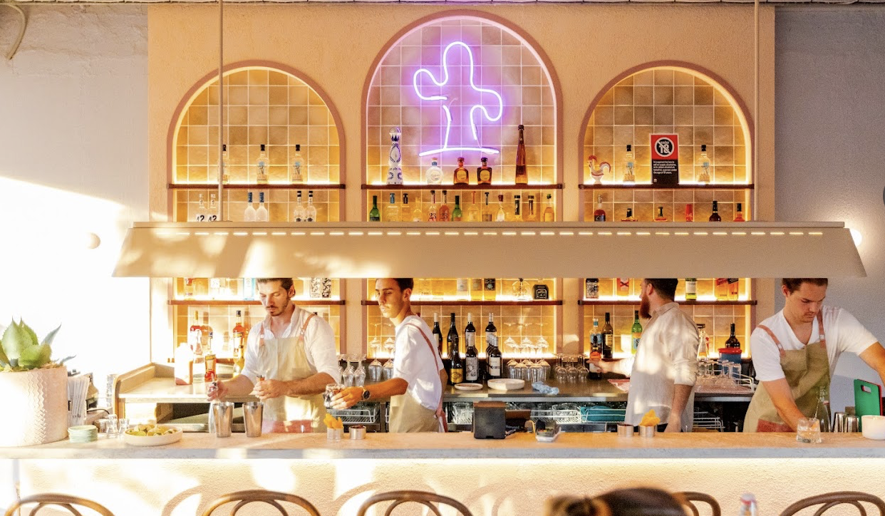 Chechos restaurant bar with illuminated arched shelving and staff behind the counter